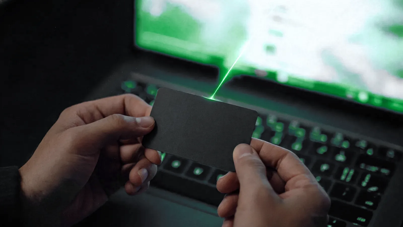 Mãos segurando um cartão diante de um notebook